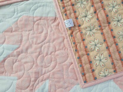 pink and white baby quilt showing cotton backing