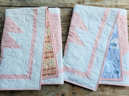 two folded baby quilts showing different backings