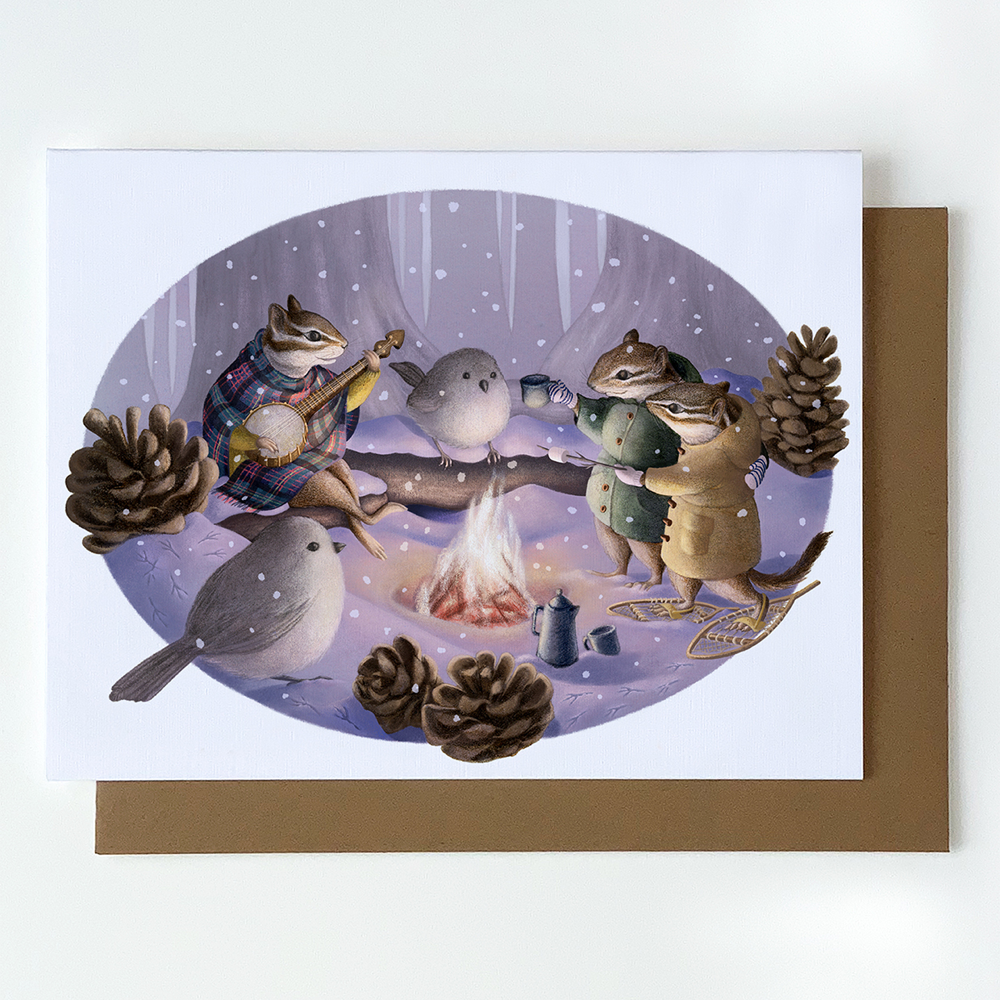 holiday greeting card of winter woodland animals around a fire celebrating, with kraft envelope